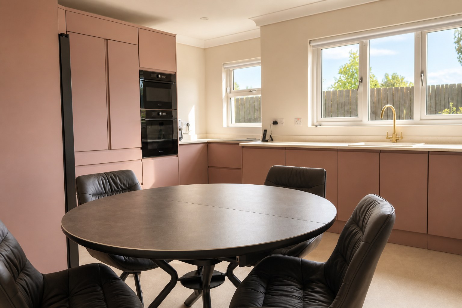 Kitchen and dining at Heron House with dusty-pink cabinets and a round table